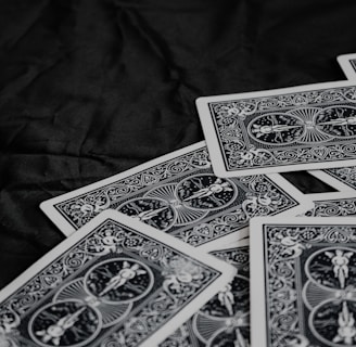 A pile of playing cards featuring intricate, symmetrical patterns on their backs, placed on a dark surface.